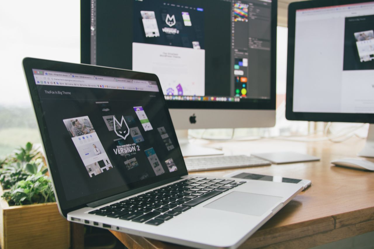 A stylish workspace with a laptop and monitors showing design software.